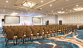 A presentation room with chairs on a stage with 2 screens on either side and empty audience chairs A presentation room with chairs on a stage with 2 screens on either side and empty audience chairs