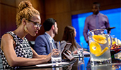A woman sitting at a conference table works on a tablet as 2 coworkers listen to a colleague
A woman sitting at a conference table works on a tablet as 2 coworkers listen to a colleague